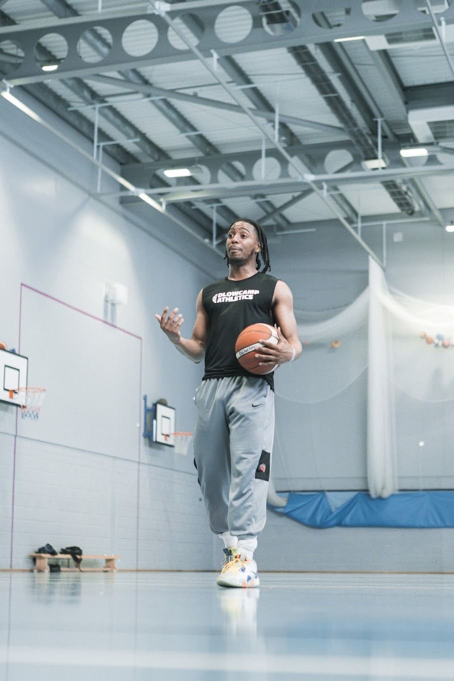 Daniel coaching a session in a Dlowcamp Athletics vest, holding a basketball