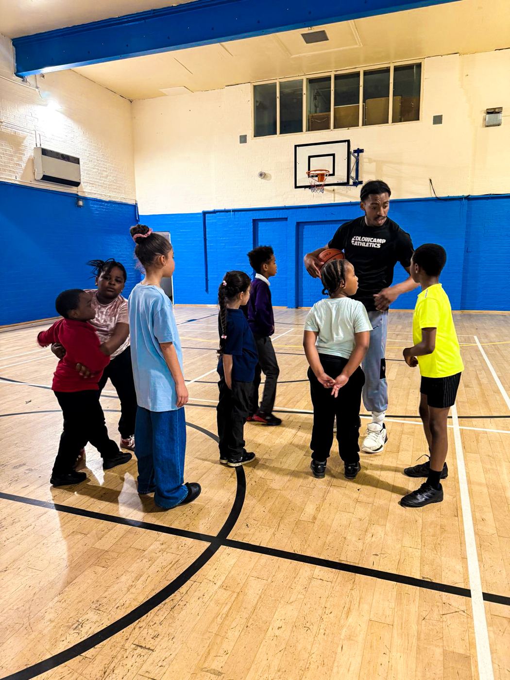 Daniel coaching a group of primary school children in a sports hall